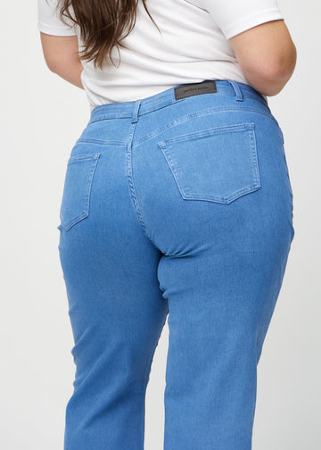 Loose jeans for women in blue, color Geraniums. Close-up from behind on a plus-size model, showing the fit and details.