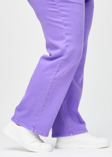 Loose jeans for women in purple, color Lavenders. Close-up at the ankles on a plus-size model, showing the wide leg openings.