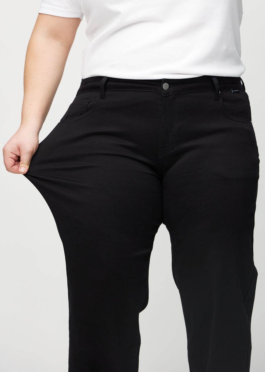 Loose jeans for women in black, color Ravens. A plus-size model stretches the denim at the thigh to show the fabric&