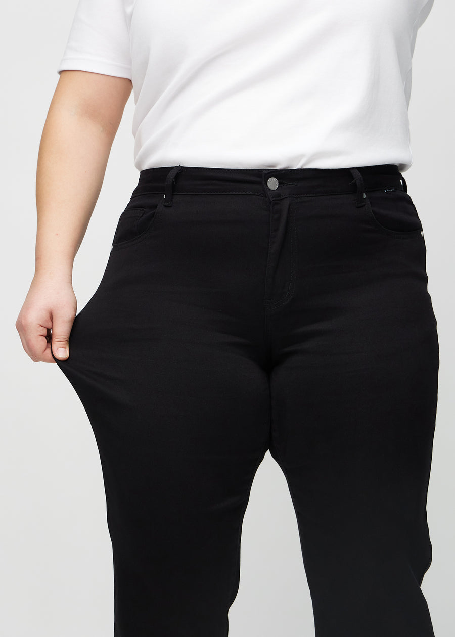 Regular jeans for women in black, color Ravens. A plus-size model stretches the fabric at the thigh to show its stretch.