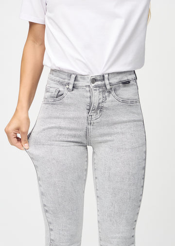 Skinny jeans for women in light grey, color Ashes. A model stretches the jeans at the thigh to show the fabric&