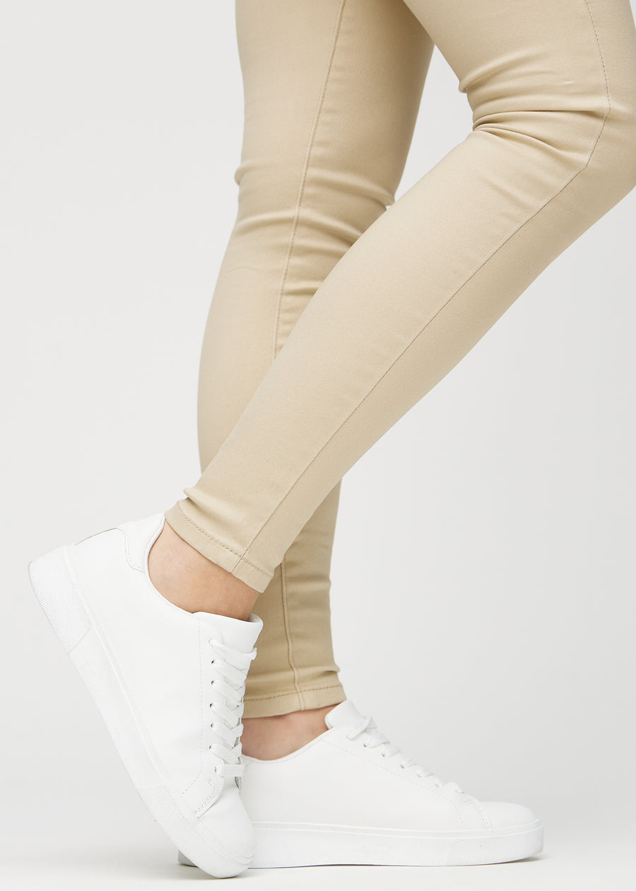 Skinny jeans for women in beige, color Gazelles. Close-up at the ankles on a model, showing the close-fitting leg openings.