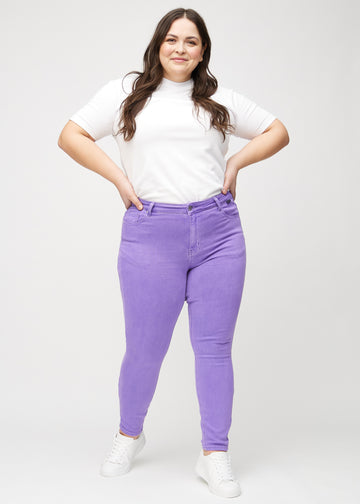 Skinny jeans for women in purple, color Lavenders. Full-length view of a plus-size model in the jeans.