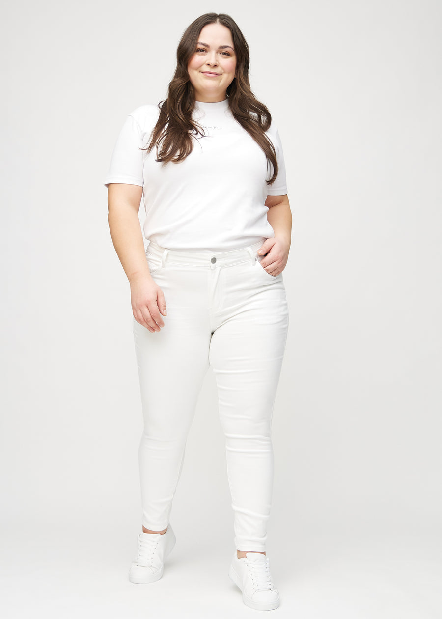 Skinny jeans for women in white, color Marguerites. Full-length view of a plus-size model in the jeans.