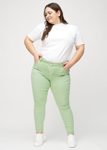 Full image of a plus-size model in light green skinny jeans.
