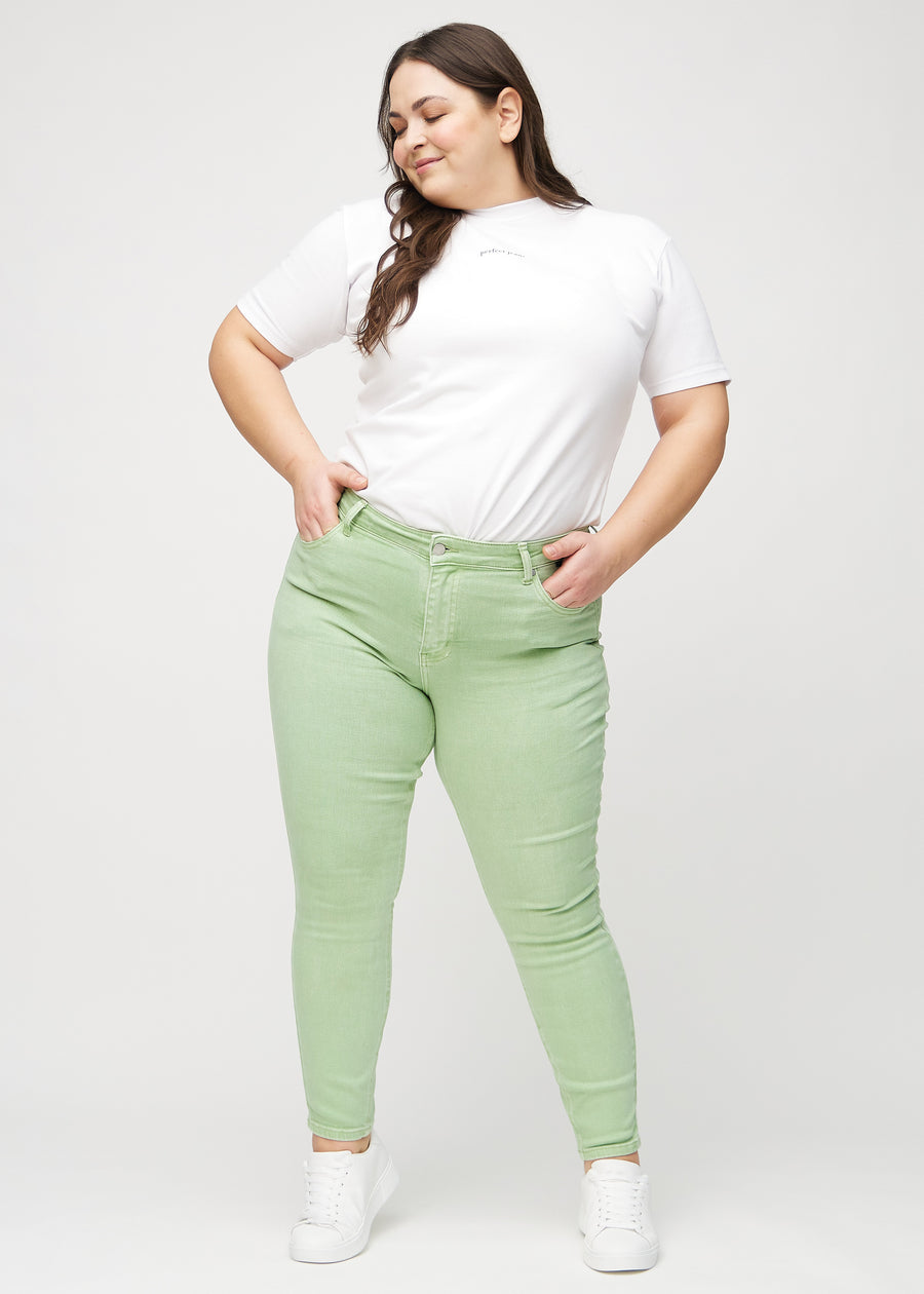 Full image of a plus-size model in light green skinny jeans.