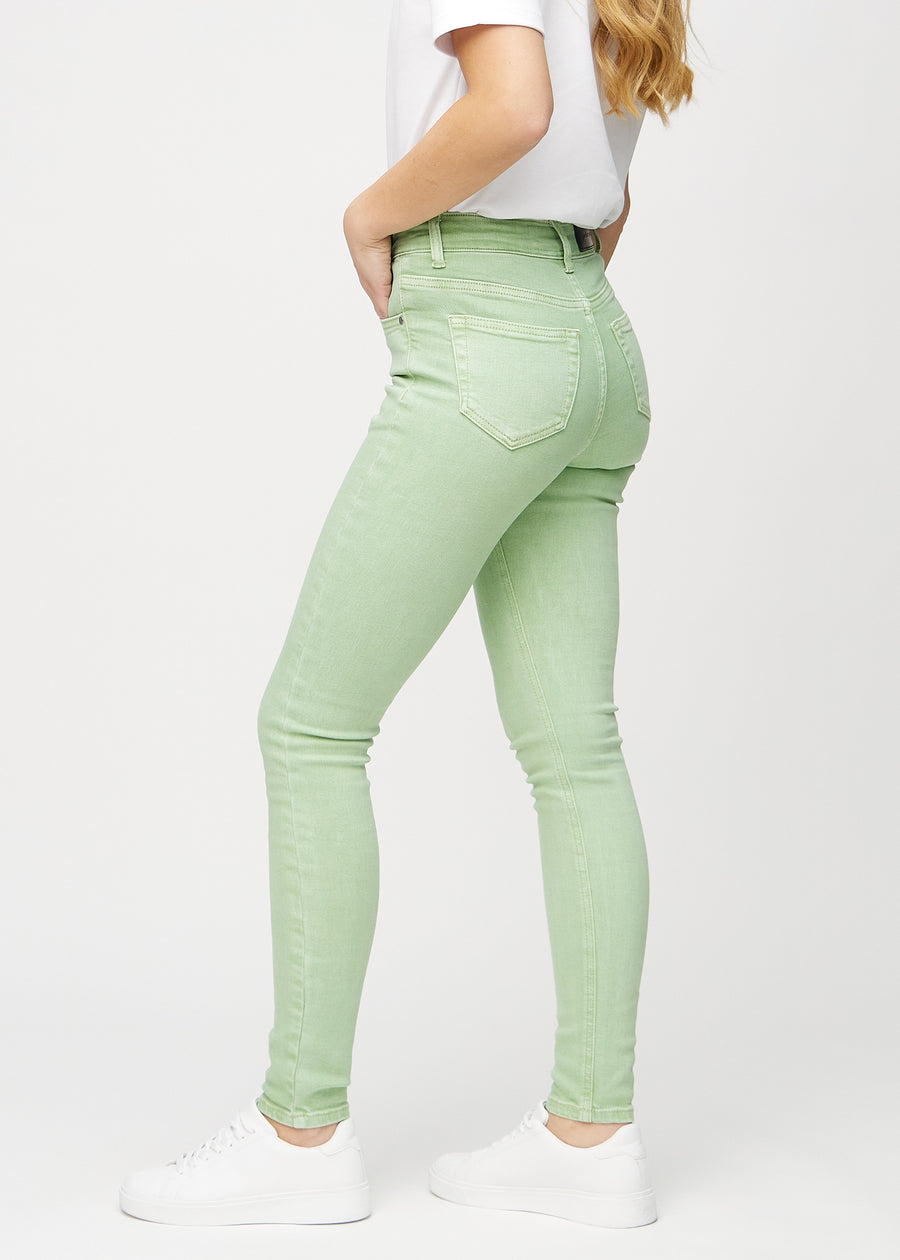 Light green skinny jeans seen from the side on a model.
