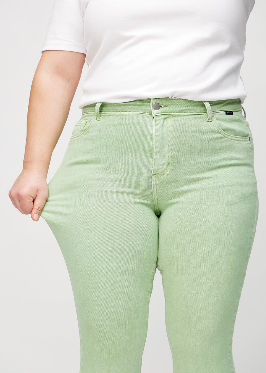 The plus-size model stretches the jeans at the thigh to show the stretch.