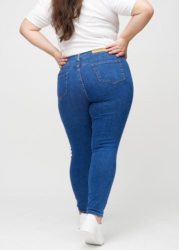 Dark denim skinny jeans seen from the back on a plus-size model, so the entire product can be seen.&