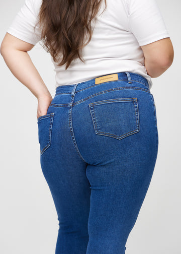 Dark denim skinny jeans seen from the back in close-up on a plus-size model to show details.