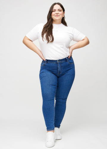 Full image of a plus-size model in dark denim skinny jeans.