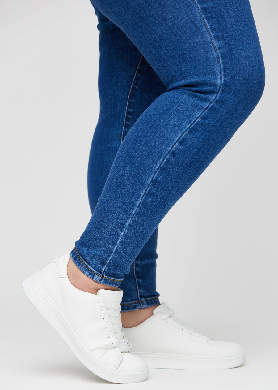 The ankles of a plus-size model, so you can see how tightly the jeans fit.