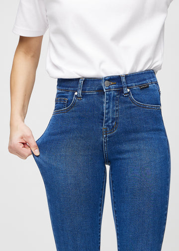The model stretches the jeans at the thigh to show the stretch.