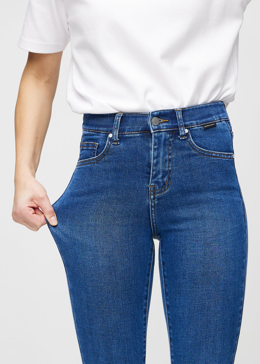 The model stretches the jeans at the thigh to show the stretch.