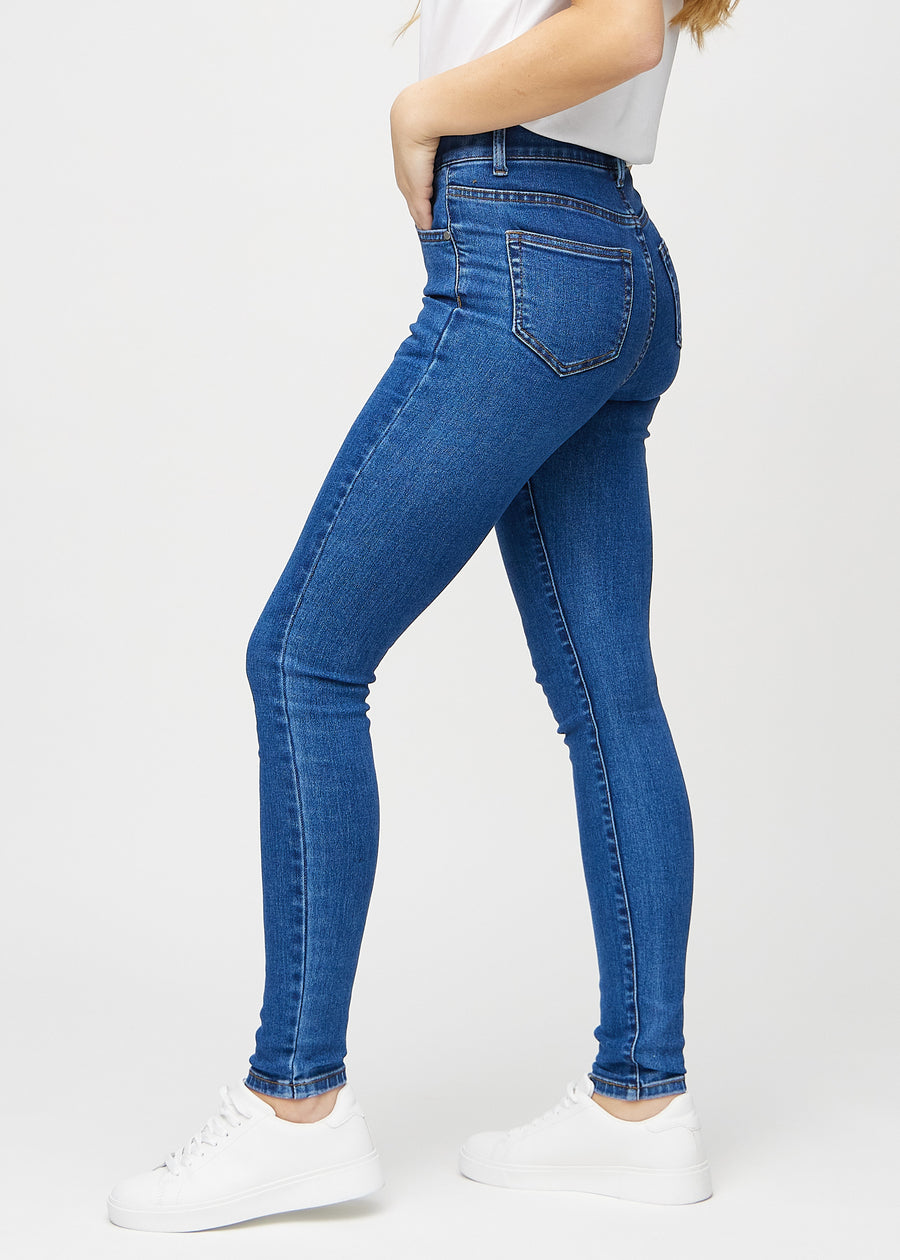 Dark denim skinny jeans seen from the side on a model.