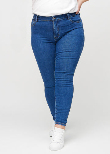 Dark denim skinny jeans, model name Oceans, which fits tightly along the leg on a plus-size model, seen from the front.