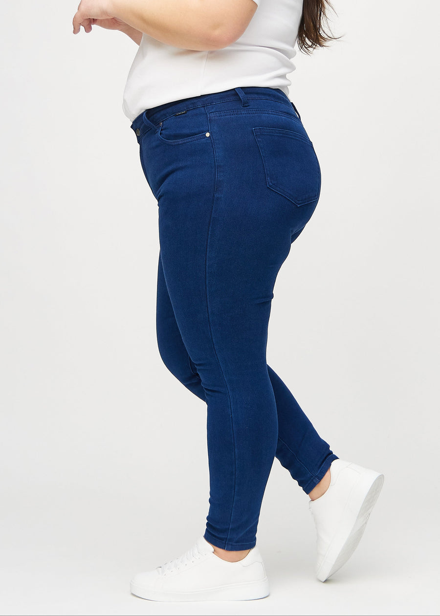 Skinny jeans for women in dark blue, color Royals. Side view on a plus-size model.