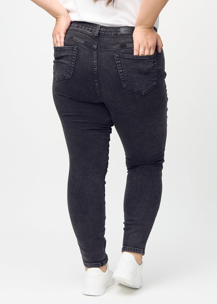 Dark grey denim skinny jeans seen from the back on a plus-size model, so the entire product can be seen.