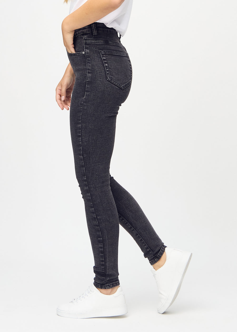 Dark grey denim skinny jeans seen from the side on a model.