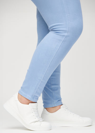 Skinny jeans for women in light blue, color Skies. Close-up at the ankles on a plus-size model, showing the close-fitting leg openings.