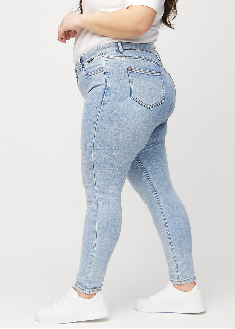 Skinny jeans for women in light blue, color Waves. Side view on a plus-size model.