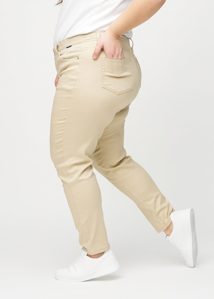 Beige slim jeans seen from the side on a plus-size model.