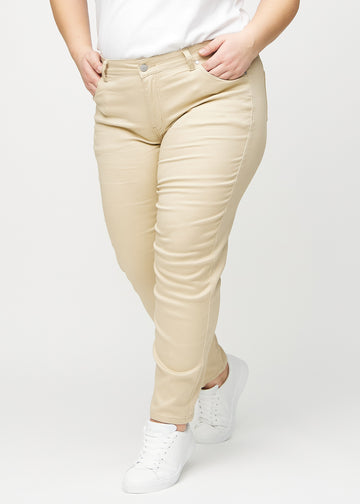 Beige slim jeans, model name Gazelles, which fits closely to the leg, though slightly looser at the ankle, though slightly looser at the ankle, on a plus-size model, seen from the front.