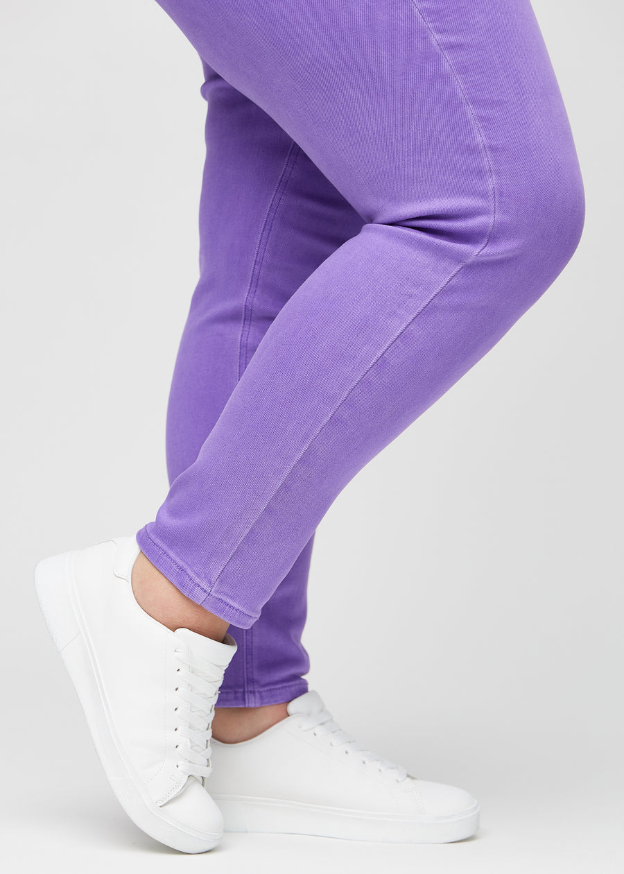 Slim jeans for women in purple, color Lavenders. Close-up at the ankles on a plus-size model, showing the fit at the leg openings.
