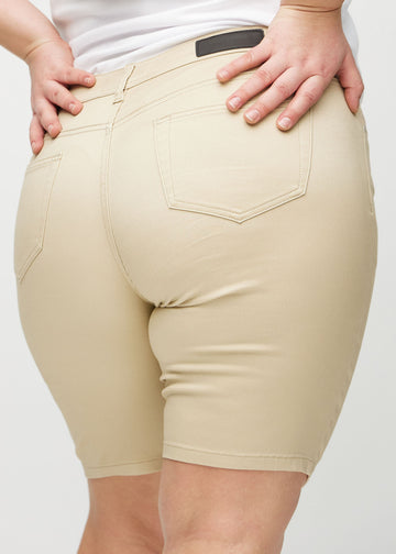 Beige skinny middle shorts seen from the back close up on a plus-size model to show details.