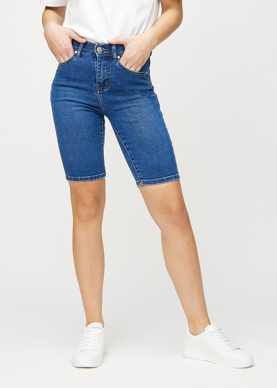 Dark denim skinny middle shorts, model name Oceans, which fit closely around the thigh and end just above the knee, seen from the front.