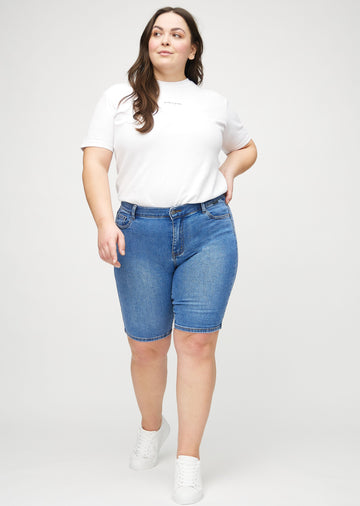 Full image of a plus-size model in denim skinny middle shorts.
