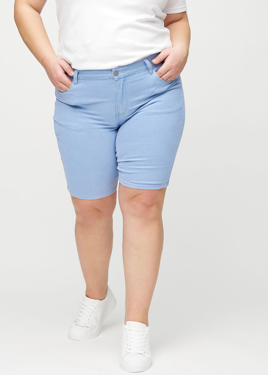 Light blue skinny middle shorts, model name Skies, which fit tightly around the thigh and end just above the knee on a plus-size model, seen from the front.