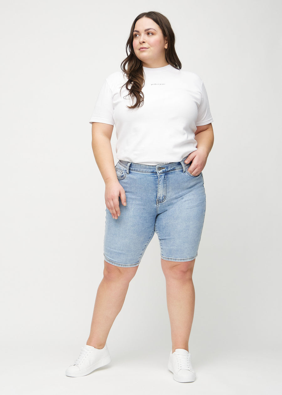 Full image of a plus-size model in light denim skinny middle shorts.