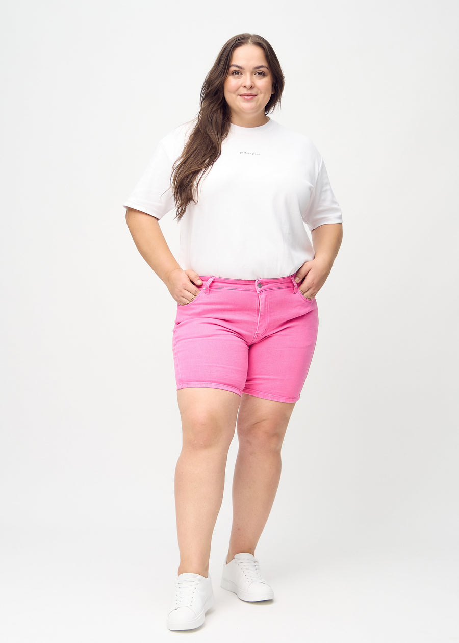 Full-length image of a plus-size model wearing light pink skinny short shorts.