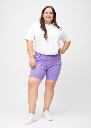 Full image of a plus-size model in purple skinny short shorts.