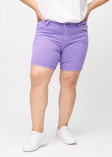 Purple skinny short shorts, style name Lavenders, with a tight fit and ending mid-thigh on a plus-size model, seen from the front.