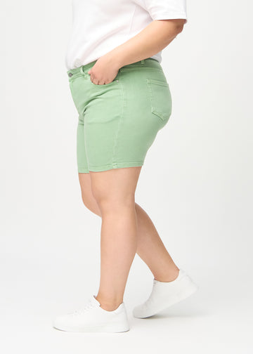 Light green skinny short shorts seen from the side on a plus-size model.