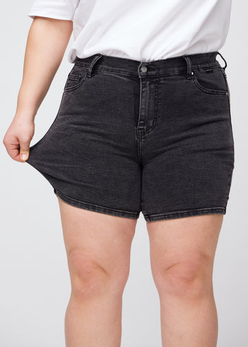 Plus-size model stretches the shorts at the thigh to show the stretch.