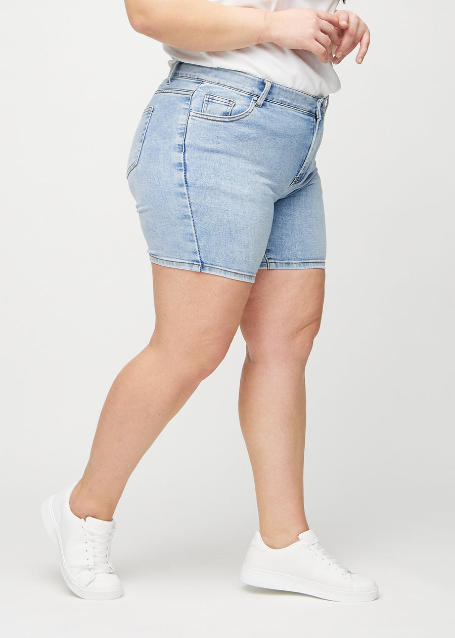 Light denim skinny short shorts seen from the side on a plus-size model.