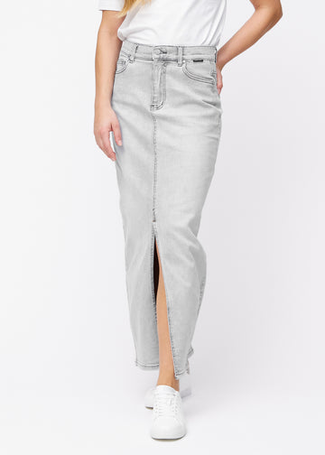 Long light grey denim skirt for women in the color Ashes. Front view on a model, showing the straight fit from the hips and a front slit starting below the knee.