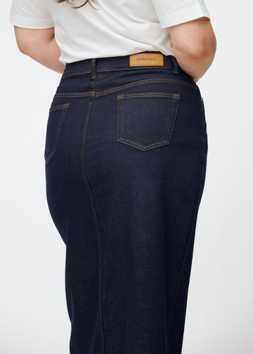 Long deep dark blue denim skirt for women in the colour Midnights seen from the back in close-up on a plus-size model to show fit and details.