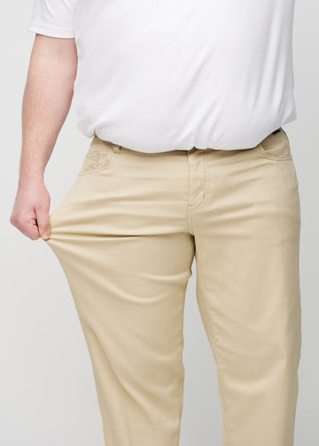 The plus-size model stretches the jeans at the thigh to show the stretch.