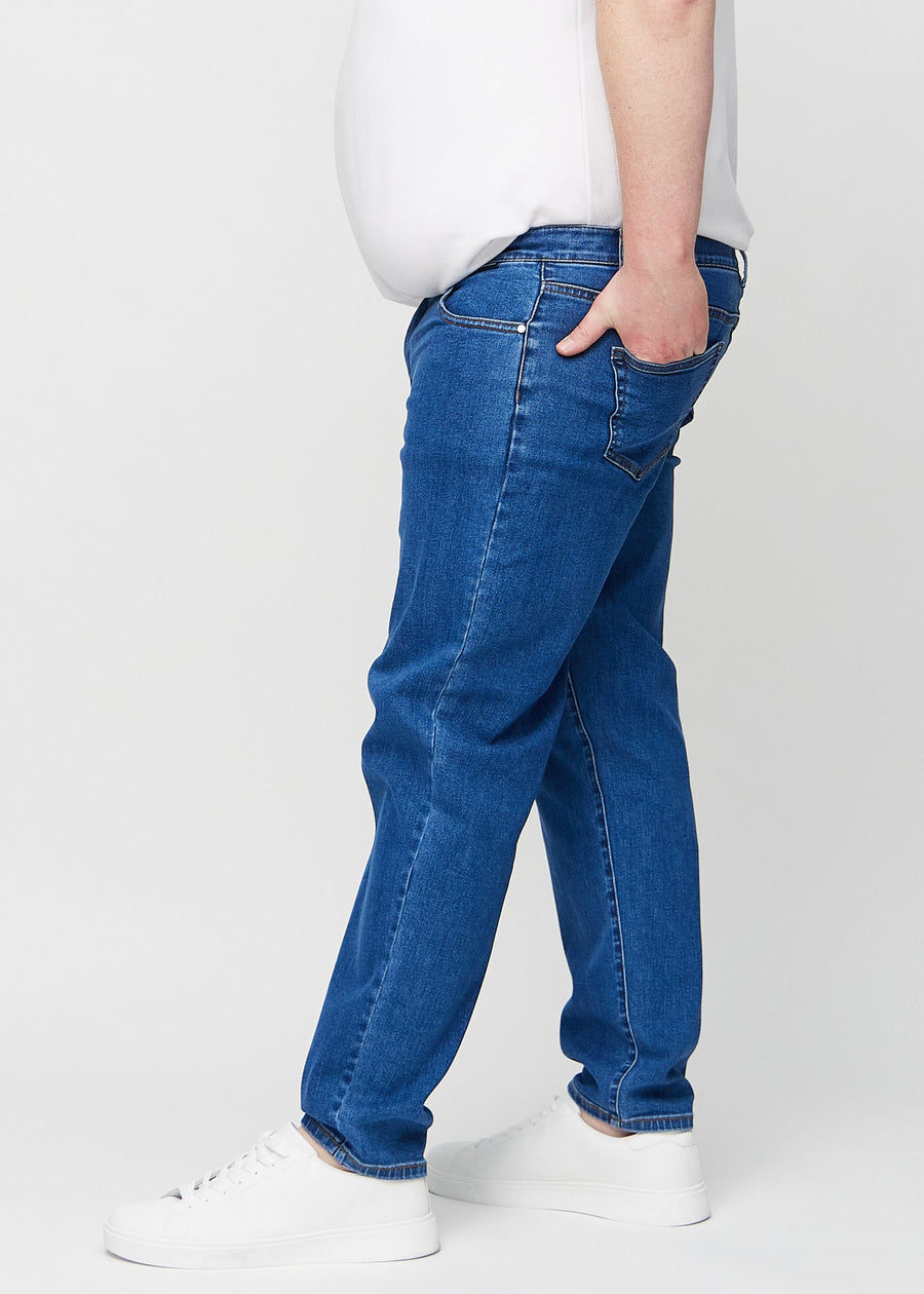 Dark blue denim regular jeans seen from the side on a plus-size model.