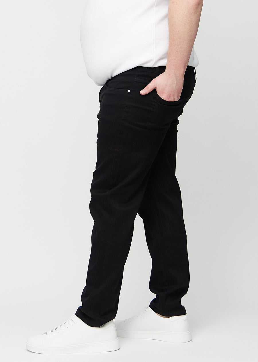 Black regular jeans seen from the side on a plus-size model.