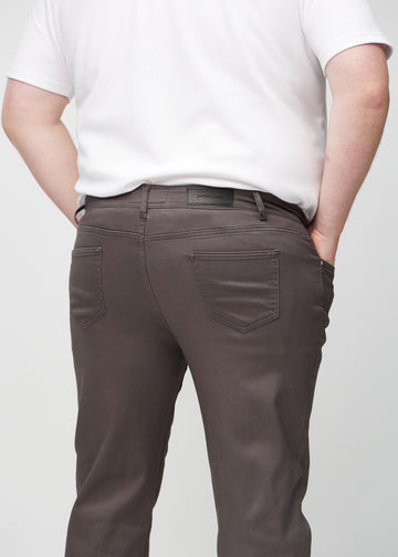 Grey-brown regular jeans seen from the back close up on a plus-size model to show details.