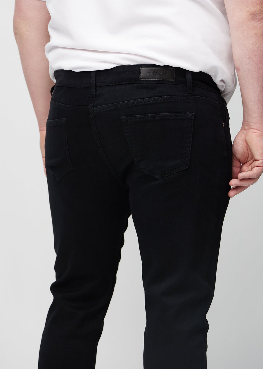 Close-up back view of black slim jeans on a plus-size model showing details.