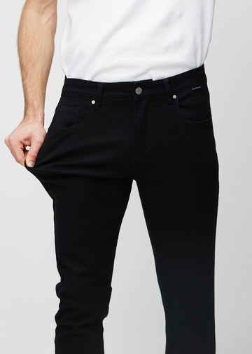 Model stretches the jeans at the thigh to show the fabric&