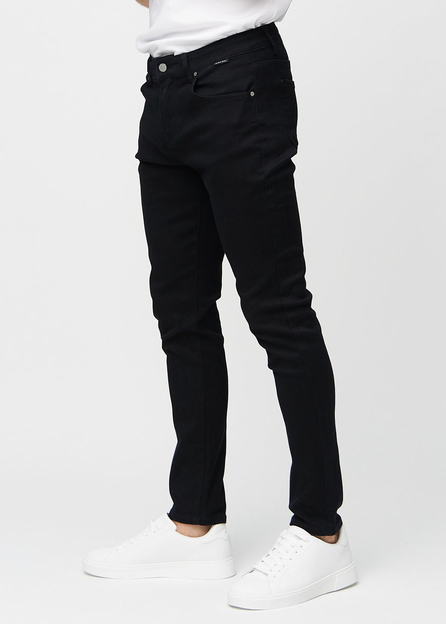 Black slim jeans viewed from the side on a model.