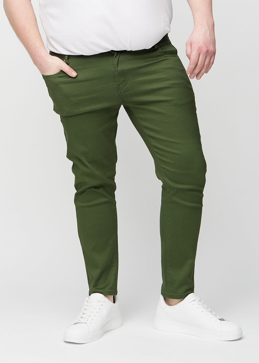 Dark green slim jeans, model name Renewals, fitted closely along the legs on a plus-size model, front view.