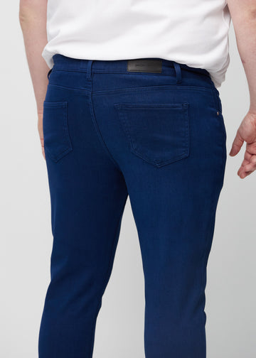Close-up back view of dark blue slim jeans on a plus-size model showing details.